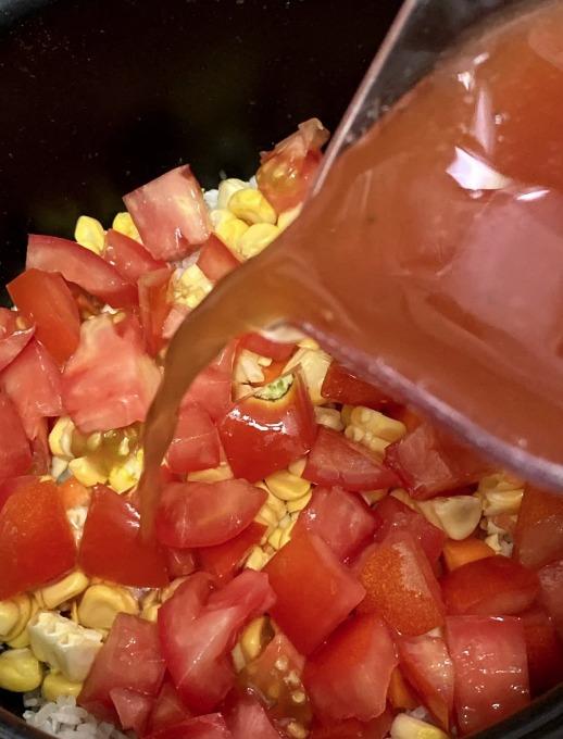 洗好米,先放入飯煲內鍋。加入蒜頭、甘筍和番茄粒。加入煮飯汁。在番茄上排入雞翼。