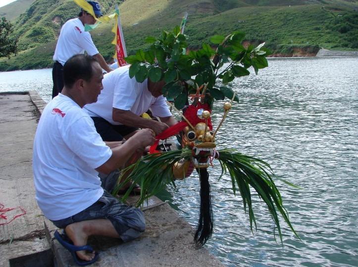 在大澳端午龍舟遊涌活動開始前,漁業行會的成員會將採集的青草,放進龍舟的龍口中,稱為「採青」。(圖片來源:香港記憶網站)