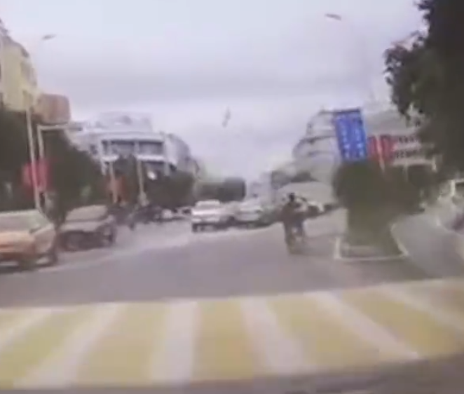 江西贛州一輛Tesla Model Y電動車行駛時,疑因緊急避讓行人操作不當,撞上道路設施和停在路邊的車輛,車輛凌空飛起,翻滾多圈砸壞路上約9輛車,造成4人受傷。(影片截圖)