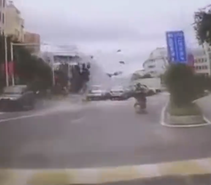 江西贛州一輛Tesla Model Y電動車行駛時,疑因緊急避讓行人操作不當,撞上道路設施和停在路邊的車輛,車輛凌空飛起,翻滾多圈砸壞路上約9輛車,造成4人受傷。(影片截圖)