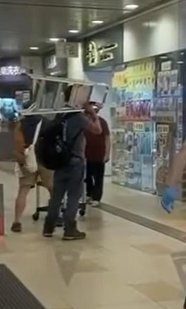 水泉澳快餐店斬人︱身穿紅色上衣的兇徒跟追上前的途人對峙,有人將收餐車推向持刀男阻止他走近,亦有人揮動一把梯打向兇徒(香港突發事故報料區fb)