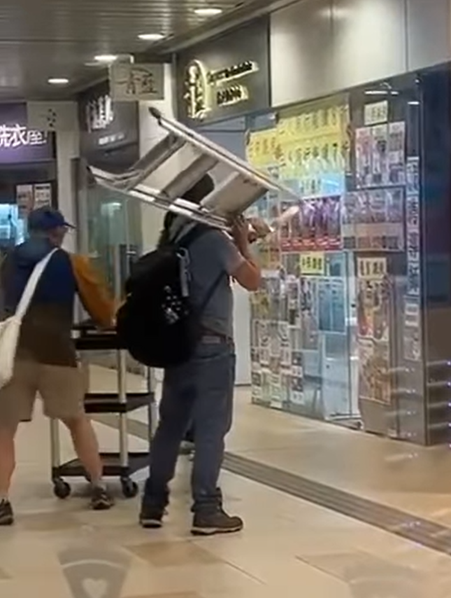 水泉澳快餐店斬人︱身穿紅色上衣的兇徒跟追上前的途人對峙,有人將收餐車推向持刀男阻止他走近,亦有人揮動一把梯打向兇徒(香港突發事故報料區fb)