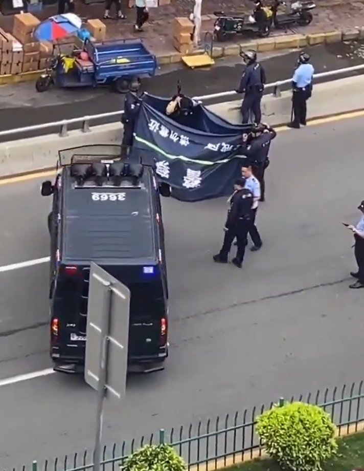 廣東東莞一名涉嫌持菜刀搶劫的男子,在虎門鎮虎門大道路中央手持菜刀架在自己的頸前方,與現場全副武裝的警方對峙,他最終被制服逮捕。(影片截圖)