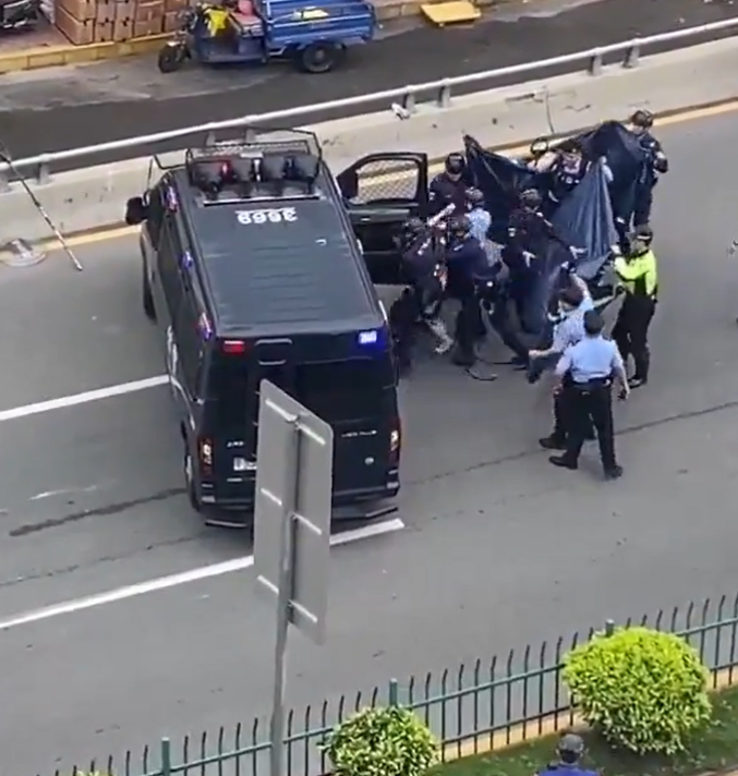 廣東東莞一名涉嫌持菜刀搶劫的男子,在虎門鎮虎門大道路中央手持菜刀架在自己的頸前方,與現場全副武裝的警方對峙,他最終被制服逮捕。(影片截圖)