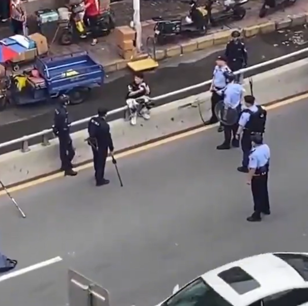 廣東東莞一名涉嫌持菜刀搶劫的男子,在虎門鎮虎門大道路中央手持菜刀架在自己的頸前方,與現場全副武裝的警方對峙,他最終被制服逮捕。(影片截圖)