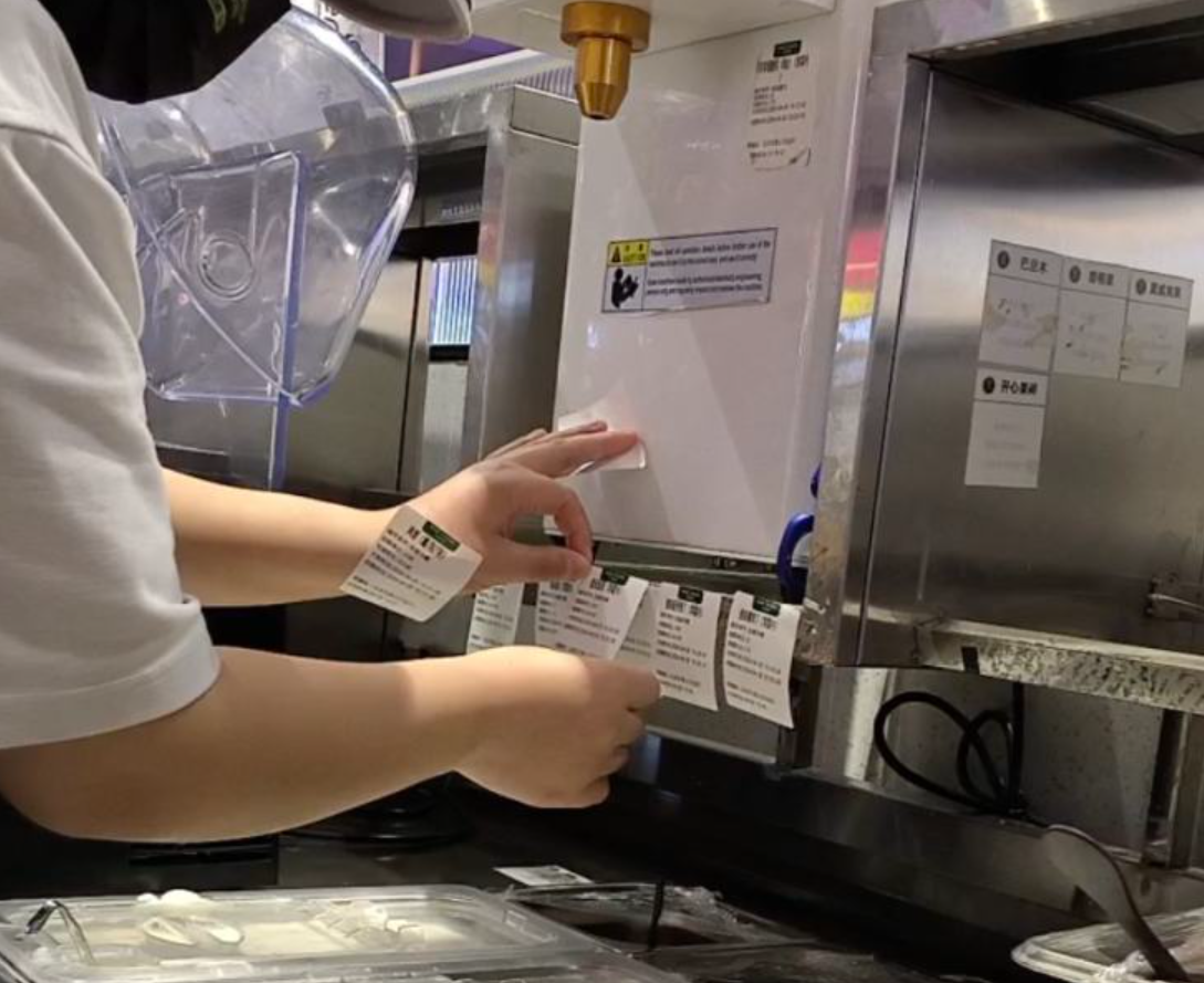 茉酸奶北京店員更換效期標簽,為過期食材「續命」。(新京報)