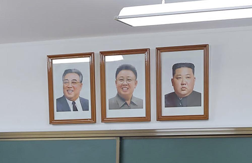 金正恩和父親金正日及爺爺金日成的肖像並列掛在學校外牆 以及教室中。(AP)