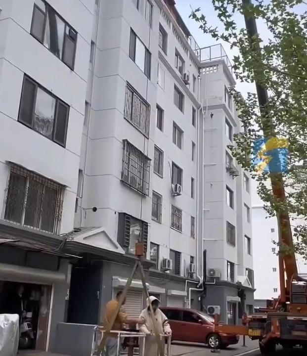 吊台載有一名女子,旁邊站著一名工人,似乎是要確保女子的安全。(微博)