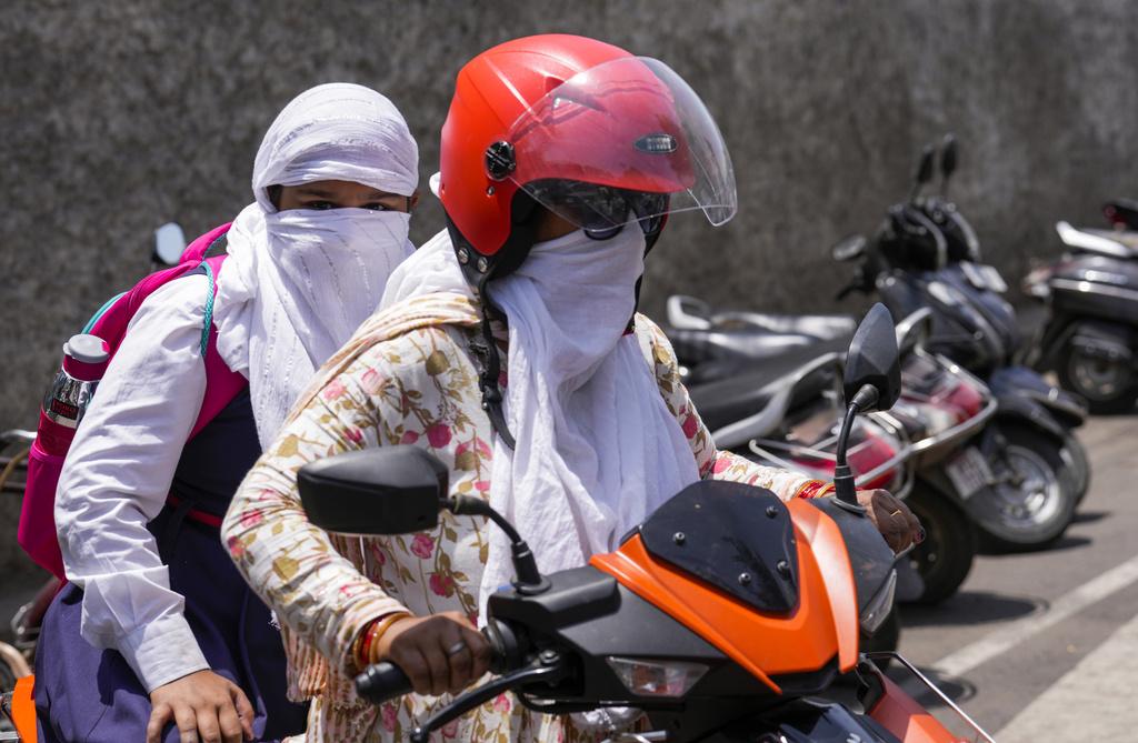 印度正遭受熱浪侵襲,民眾外出時做足防曬。(美聯社)