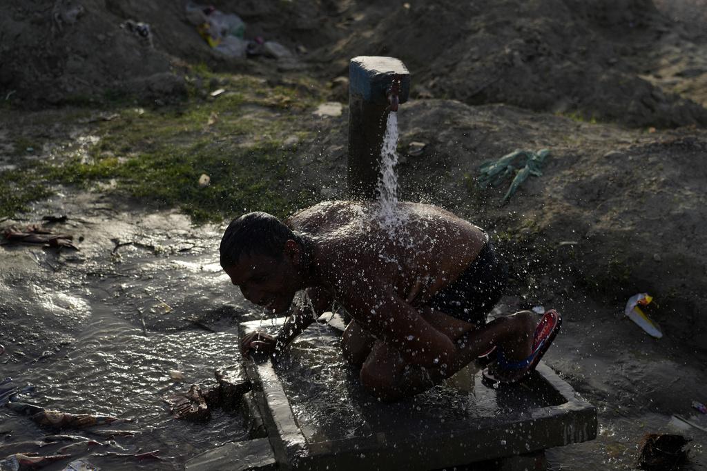 印度正遭受熱浪侵襲,民眾淋水降溫。(美聯社)