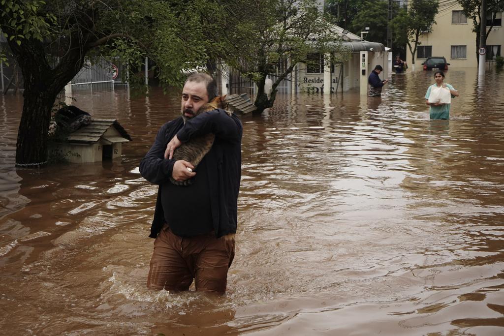 巴西南大河州水災持續,有居民與貓咪涉水撤離。(美聯社)