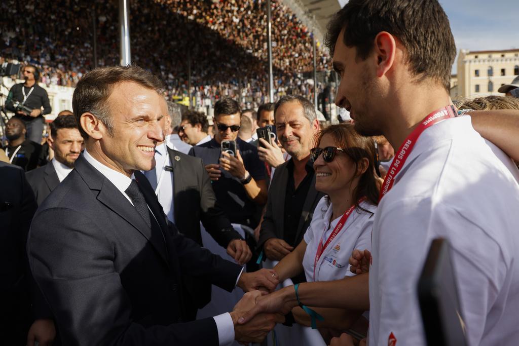 法國南部城市馬賽上周舉行奧運聖火傳遞活動,總統馬克龍(左)與參加者互動。(美聯社)