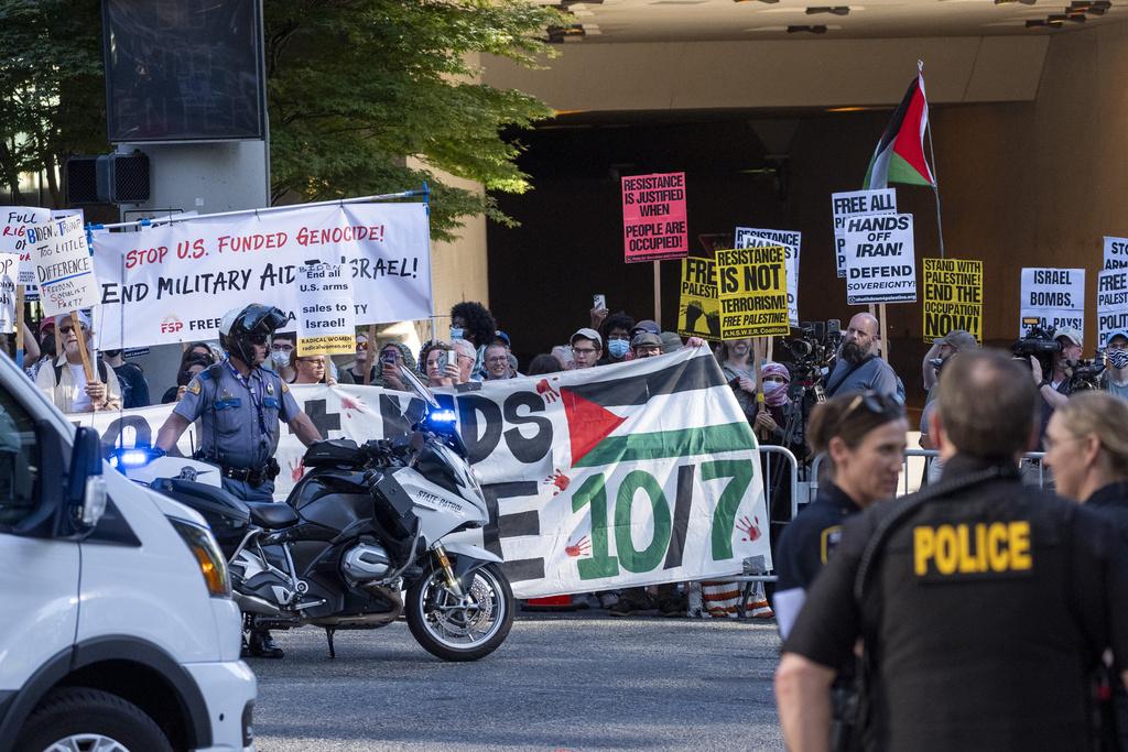 拜登上周五在西雅圖一間酒店舉行競選籌款活動,場外有民眾舉牌抗議。(美聯社)