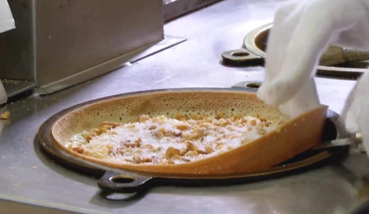 冷糕是用一個圓形大平底鑊製成,將麵粉漿加入鑊中,隨即蓋上鑊蓋,一會後金黃香脆的糕底便完成。取出後灑上芝麻、花生、椰絲、砂糖等,待有客人時,便切成八至十多份售賣。(網上截圖)