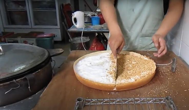 冷糕是用一個圓形大平底鑊製成,將麵粉漿加入鑊中,隨即蓋上鑊蓋,一會後金黃香脆的糕底便完成。取出後灑上芝麻、花生、椰絲、砂糖等,待有客人時,便切成八至十多份售賣。(網上截圖)
