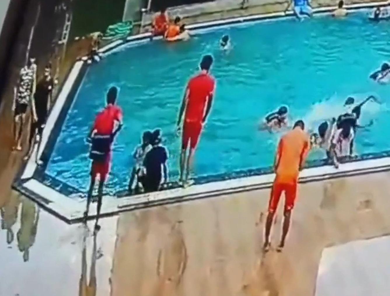 蒂瓦里跌進水裡。兩名穿紅衣的救生員站在池邊觀看。(互聯網)