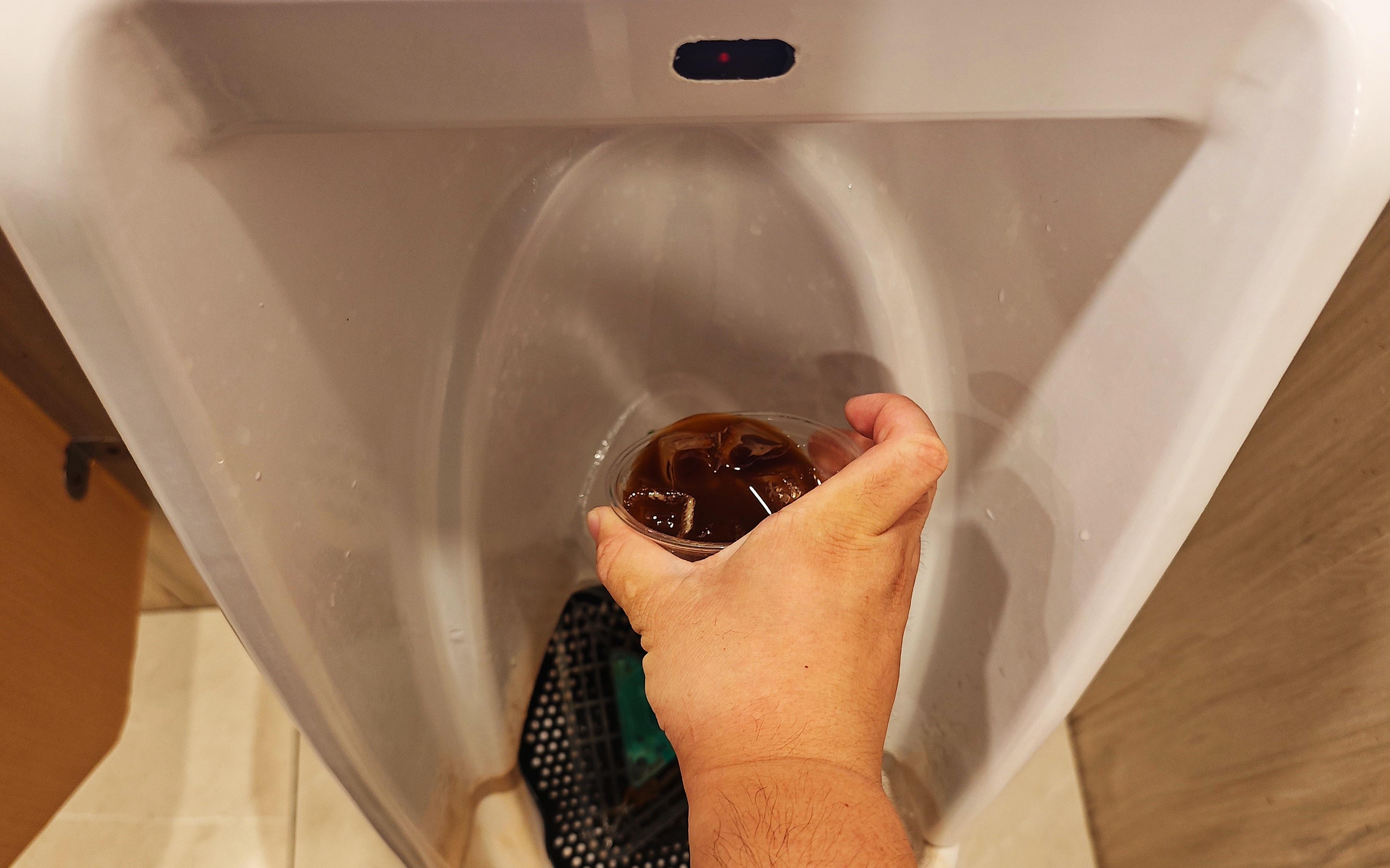記者倒一杯咖啡到小便池。(新京報圖片)
