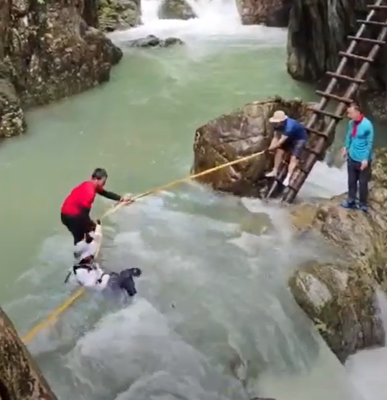 浙江台州石人峽景區有一男一女遊客用繩索橫渡峽谷溪流時,被水沖走(影片截圖)