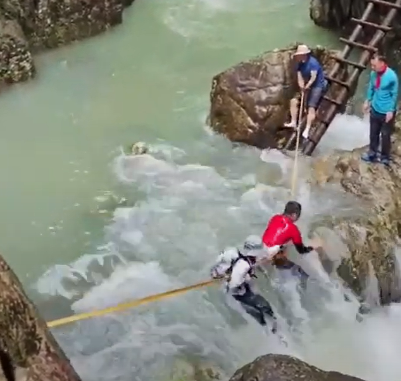 浙江台州石人峽景區有一男一女遊客用繩索橫渡峽谷溪流時,被水沖走(影片截圖)