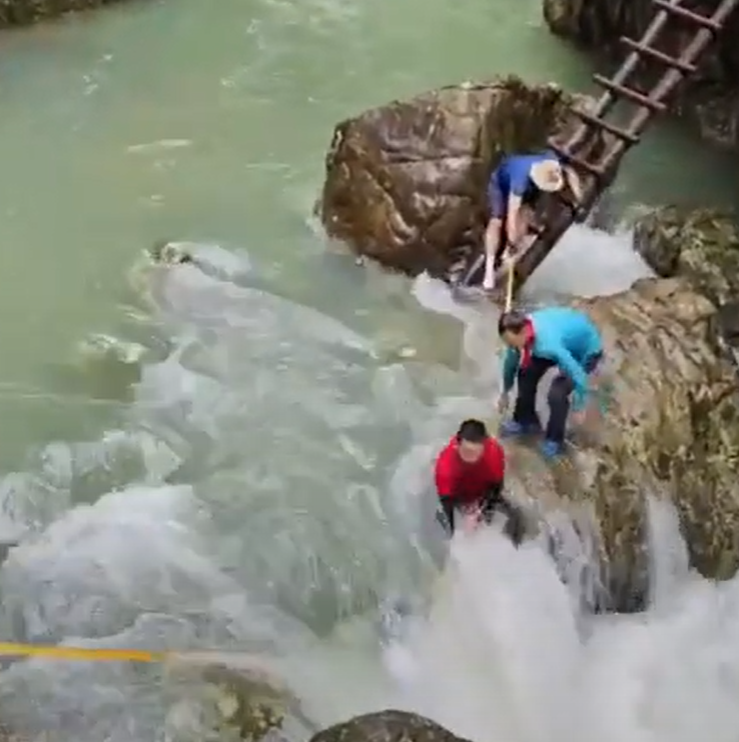 浙江台州石人峽景區有一男一女遊客用繩索橫渡峽谷溪流時,被水沖走(影片截圖)