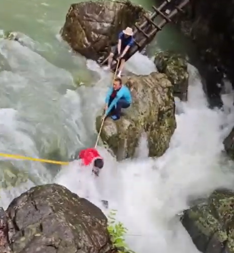 浙江台州石人峽景區有一男一女遊客用繩索橫渡峽谷溪流時,被水沖走(影片截圖)