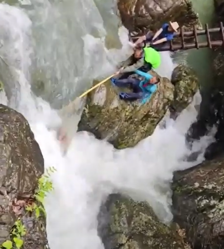 浙江台州石人峽景區有一男一女遊客用繩索橫渡峽谷溪流時,被水沖走(影片截圖)