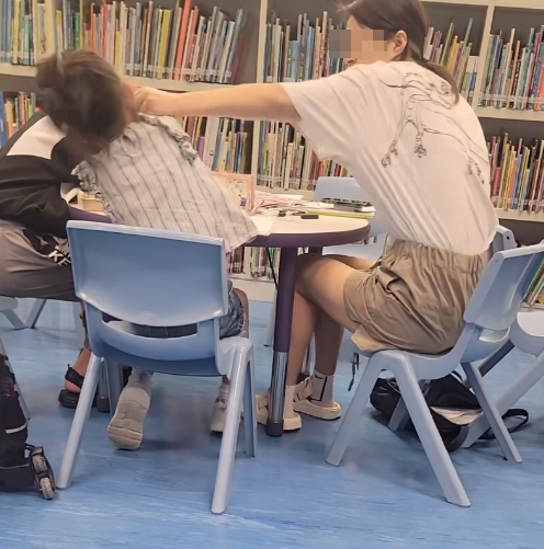 一名母親懷疑在公共圖書館內因功課問題,多次掌摑及用粗言穢語責罵7歲女兒,及後在後樓梯繼續掌摑女兒(影片截圖)