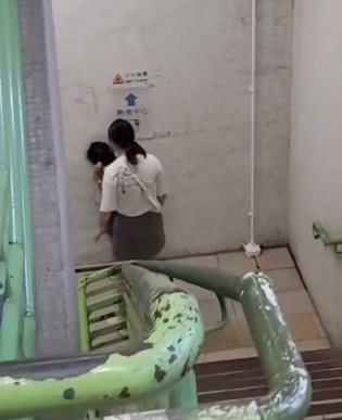 一名母親懷疑在公共圖書館內因功課問題,多次掌摑及用粗言穢語責罵7歲女兒,及後在後樓梯繼續掌摑女兒(影片截圖)
