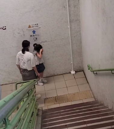 一名母親懷疑在公共圖書館內因功課問題,多次掌摑及用粗言穢語責罵7歲女兒,及後在後樓梯繼續掌摑女兒(影片截圖)