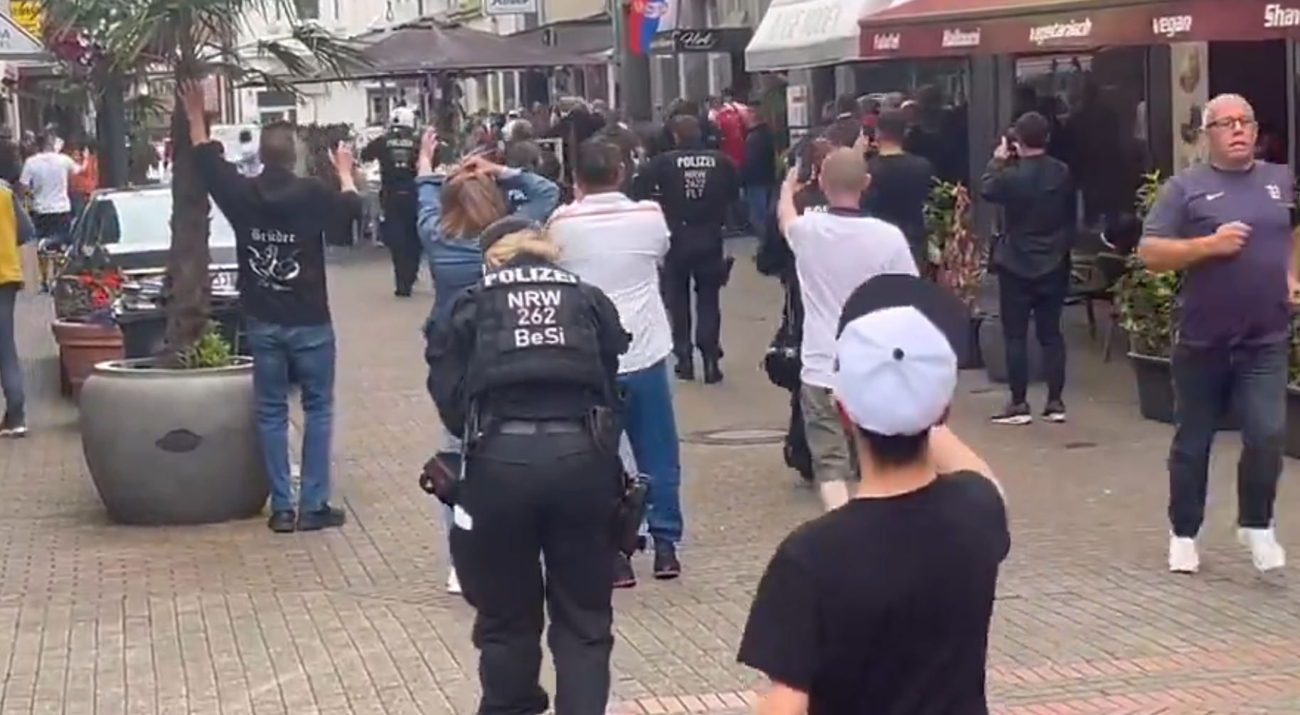 歐洲國家盃|網上片段顯示,在一間掛有塞爾維亞國旗的餐廳外,兩批男子互相打鬥子,期間有人用座椅作攻擊武器,亦有人投擲玻璃杯。(影片截圖)