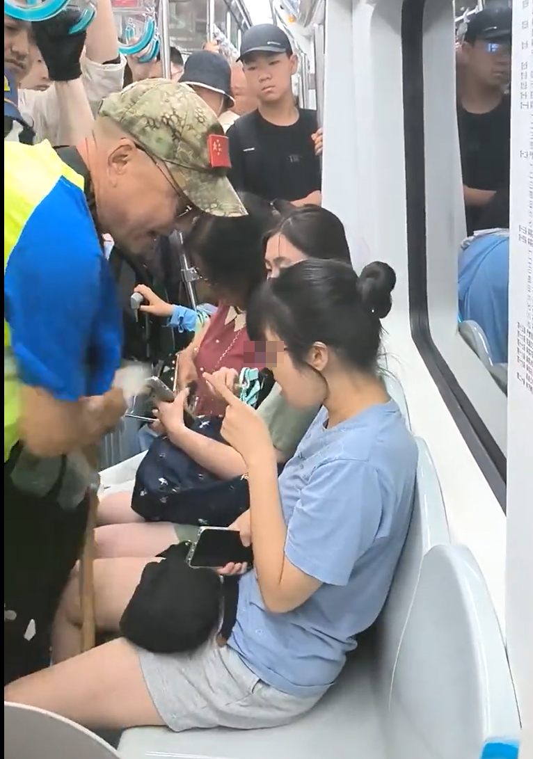 北京地鐵一名老翁不滿女乘客拒讓座,用枴杖狂撩女子雙腿中間來回「橫掃」。(影片截圖)