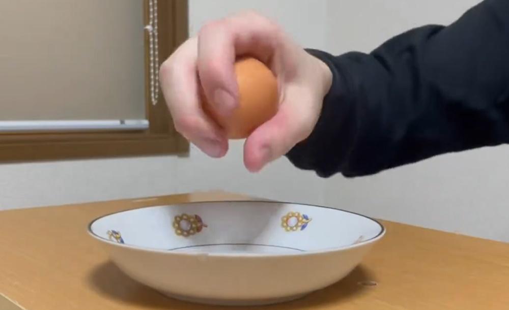 他以同樣的姿勢拿起一隻生雞蛋。(X)