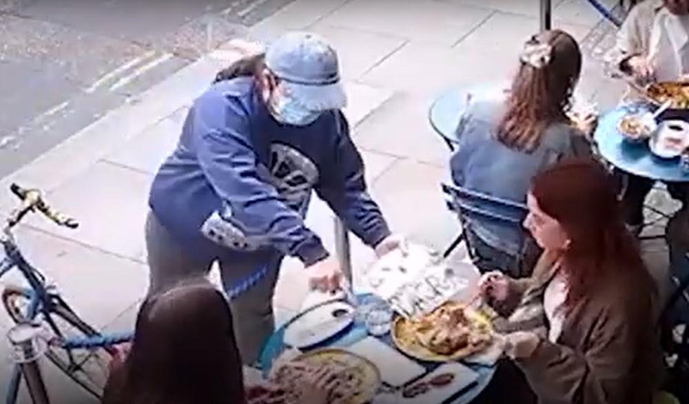 一名口罩女上前到Isolde的座位旁,左手還拿著乞食的標語牌,右手指著餐點。(YouTube)