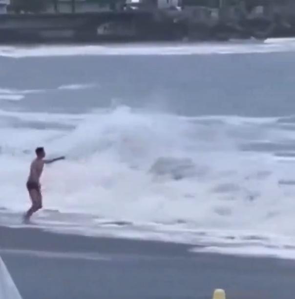 男子最終只能無助地的看著女友被捲入海裡。(X)