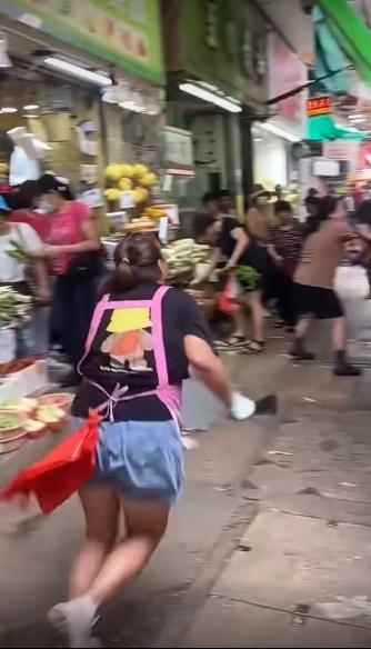 女店員在生果檔前擸起一把榴槤刀奔向婦人。(網片截圖)