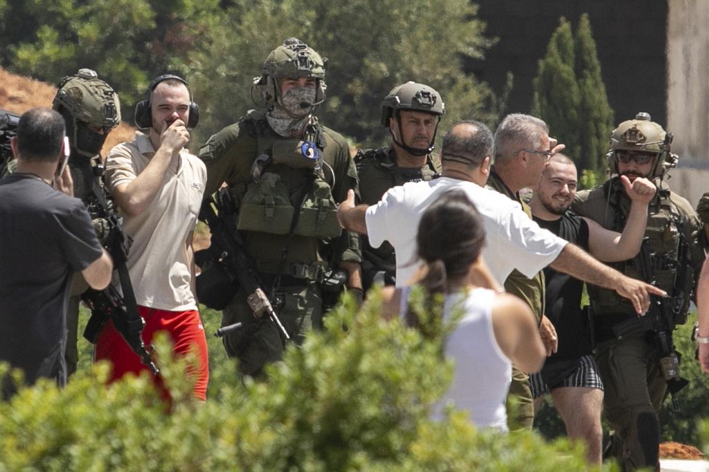 獲救人質Andrey Kozlov(白衣者)與梅爾(黑衣者)上周六乘乘直升機飛抵以色列一間醫院。(美聯社)