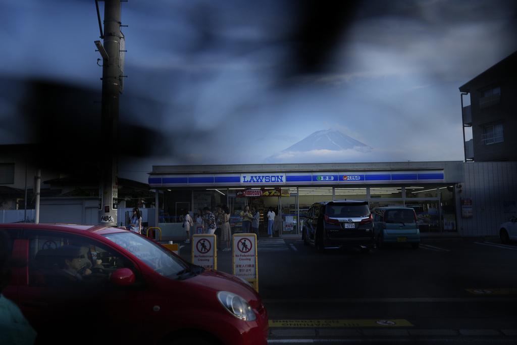 河口湖站前LAWSON便利店與富士山同框而成為遊客打卡熱點,因而飽受過度旅遊困擾,當局設置黑幕阻擋拍攝,又被挖洞。(資料圖片)