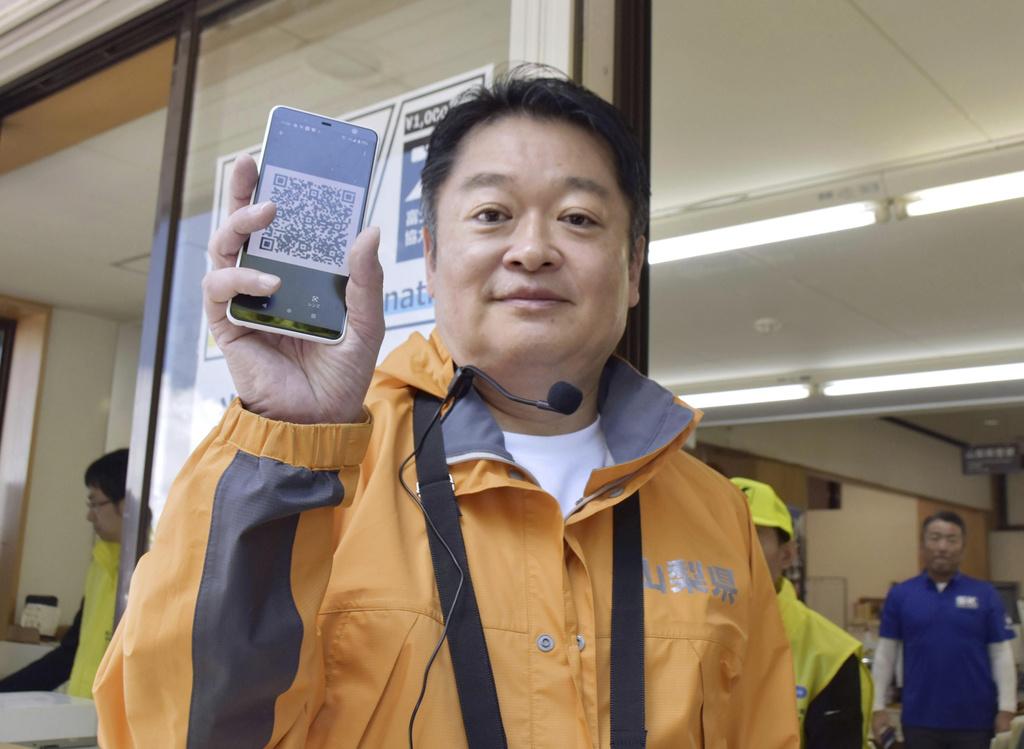 山梨縣知事長崎幸太郎展示通過閘門所需的QR code。(資料圖片)