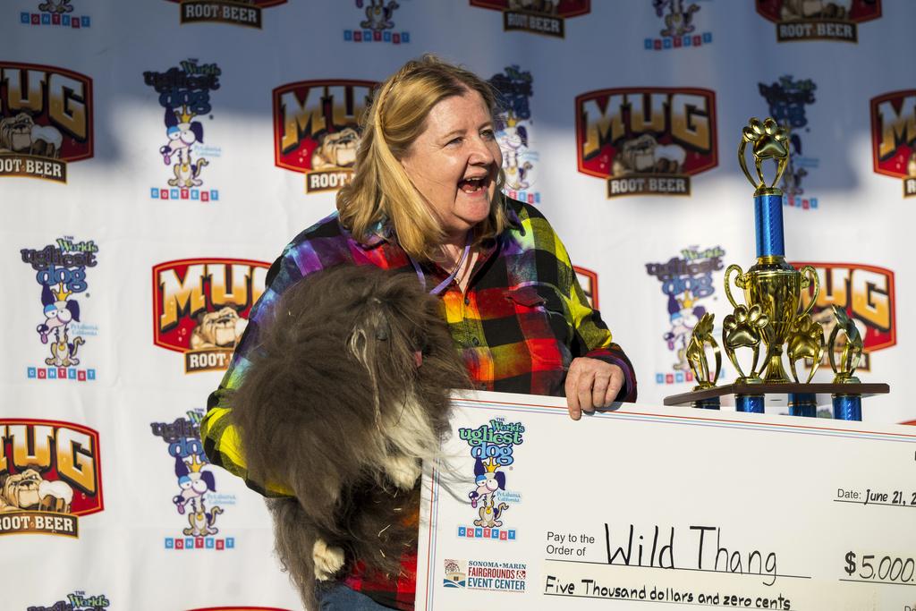 今年世界最醜狗狗比賽,由8歲北京狗Wild Thang奪冠,與主人路易斯上台領獎金。(美聯社)