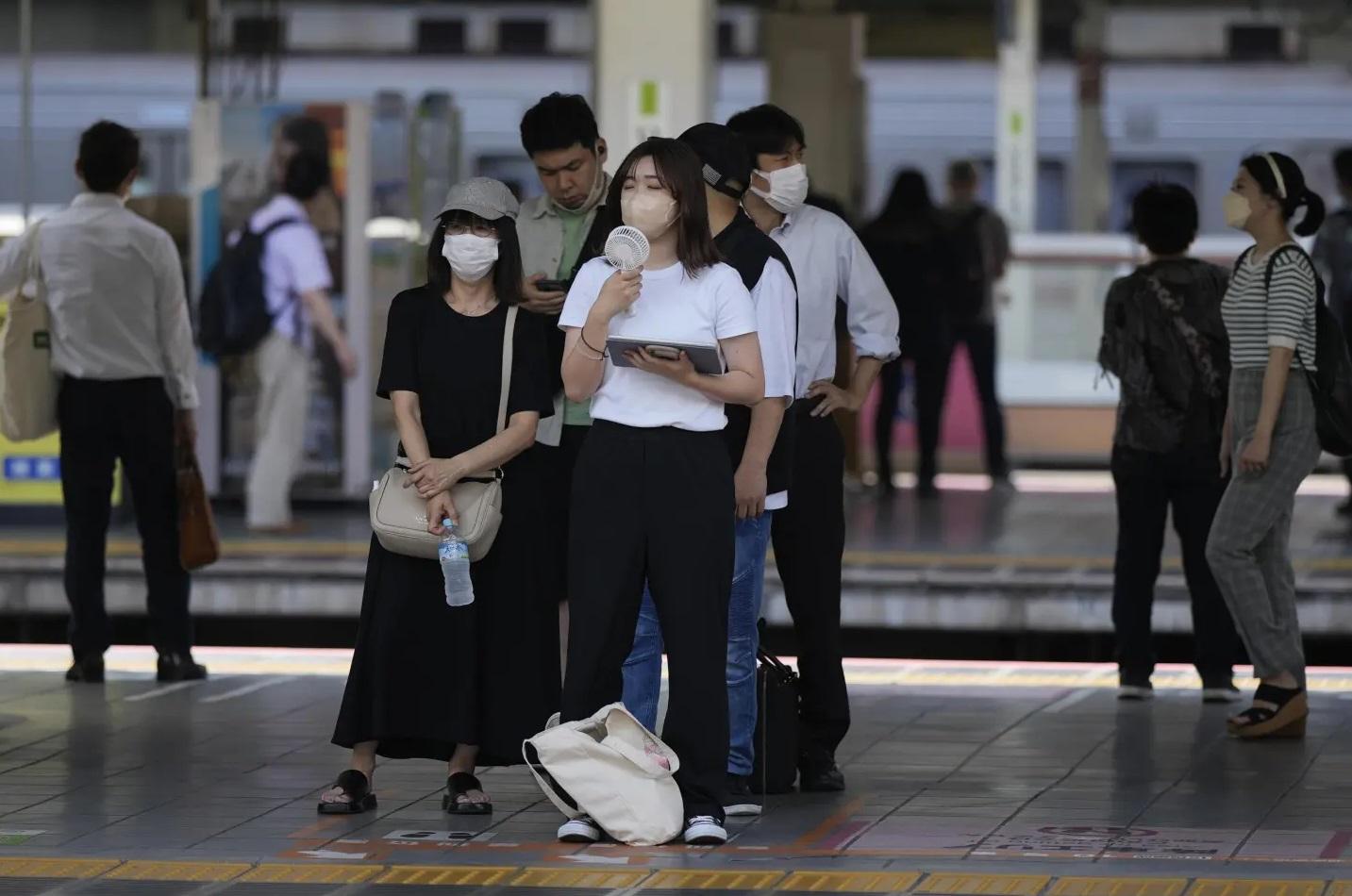 圖為東京往年炎夏,民眾有月台候車時用小風扇降溫。(資料圖片)