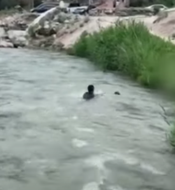 河北保定一名男孩於河邊滑倒被激流捲走,橋上一名大叔奮不顧身跳入水中,以「攔網式」將男孩救起。(影片截圖)