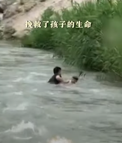 河北保定一名男孩於河邊滑倒被激流捲走,橋上一名大叔奮不顧身跳入水中,以「攔網式」將男孩救起。(影片截圖)