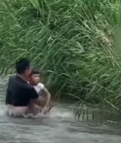 河北保定一名男孩於河邊滑倒被激流捲走,橋上一名大叔奮不顧身跳入水中,以「攔網式」將男孩救起。(影片截圖)