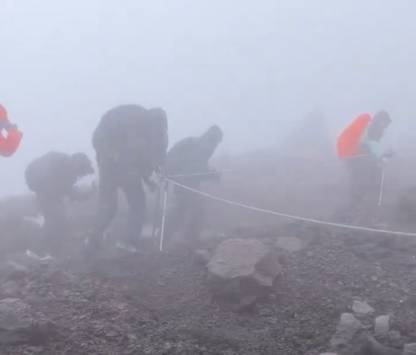富士山的暴風雨下登山遊客。(影片截圖)