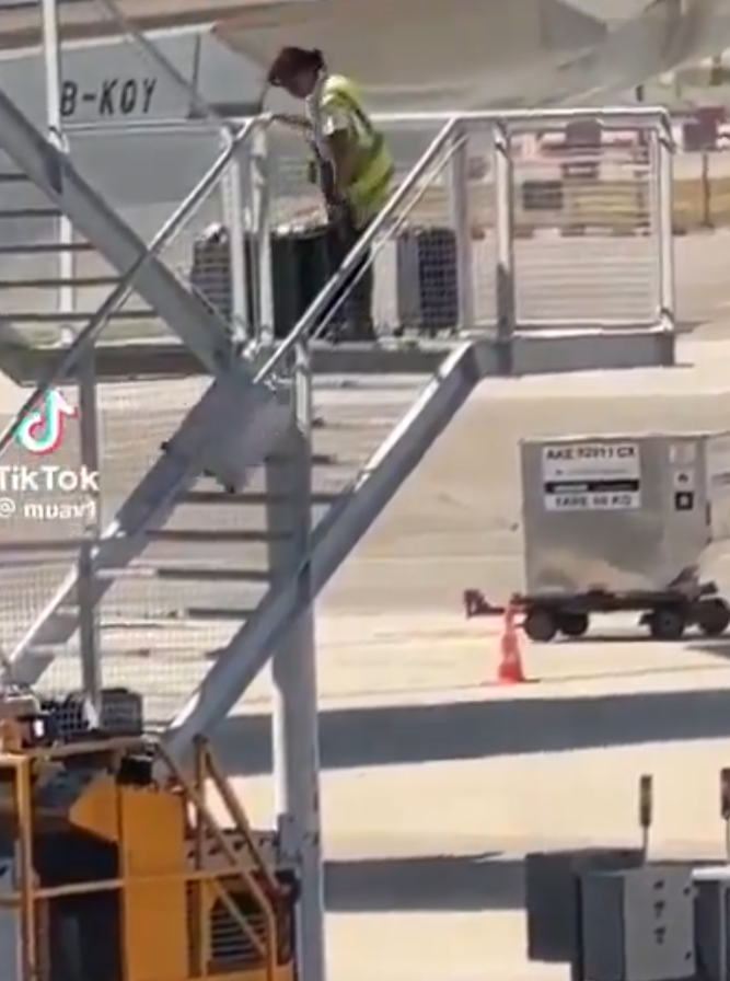 有影片顯示國泰航空的一名員工在機場多次從樓梯上把行李箱扔下(影片截圖)