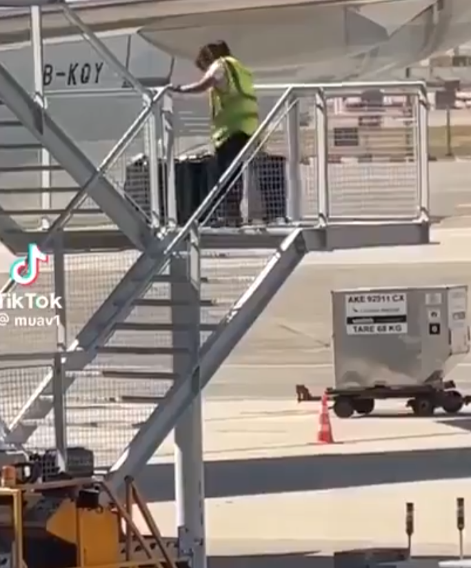 有影片顯示國泰航空的一名員工在機場多次從樓梯上把行李箱扔下(影片截圖)