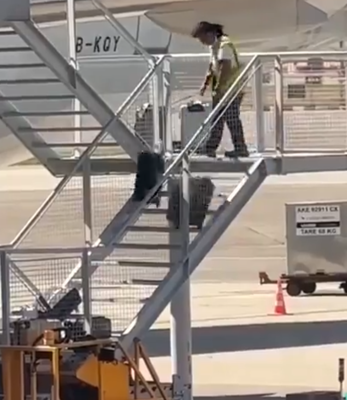有影片顯示國泰航空的一名員工在機場多次從樓梯上把行李箱扔下(影片截圖)