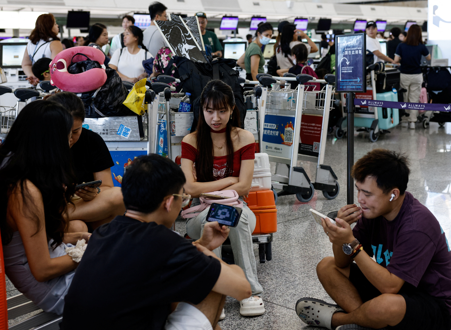 位於香港國際機場的自助辦理登機手續設施以及機場櫃位登機系統受到影響,航空公司為旅客人手辦理登機手續。(路透社)