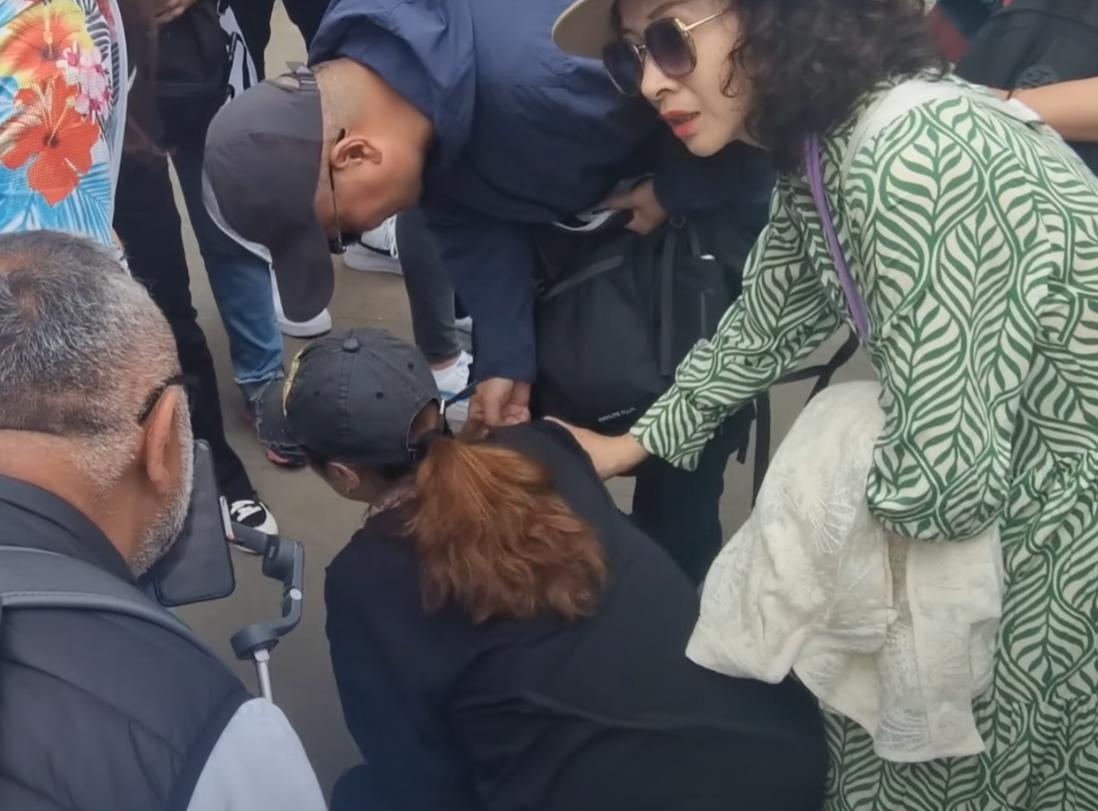 該名女遊客蹲在地上單手撐地,更在友人為其處理傷口時暈倒。(影片截圖)