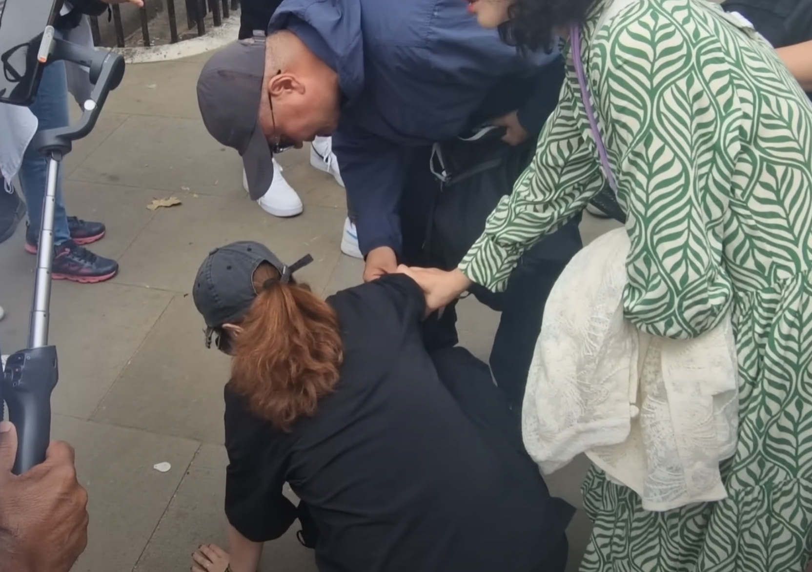 該名女遊客蹲在地上單手撐地,更在友人為其處理傷口時暈倒。(影片截圖)